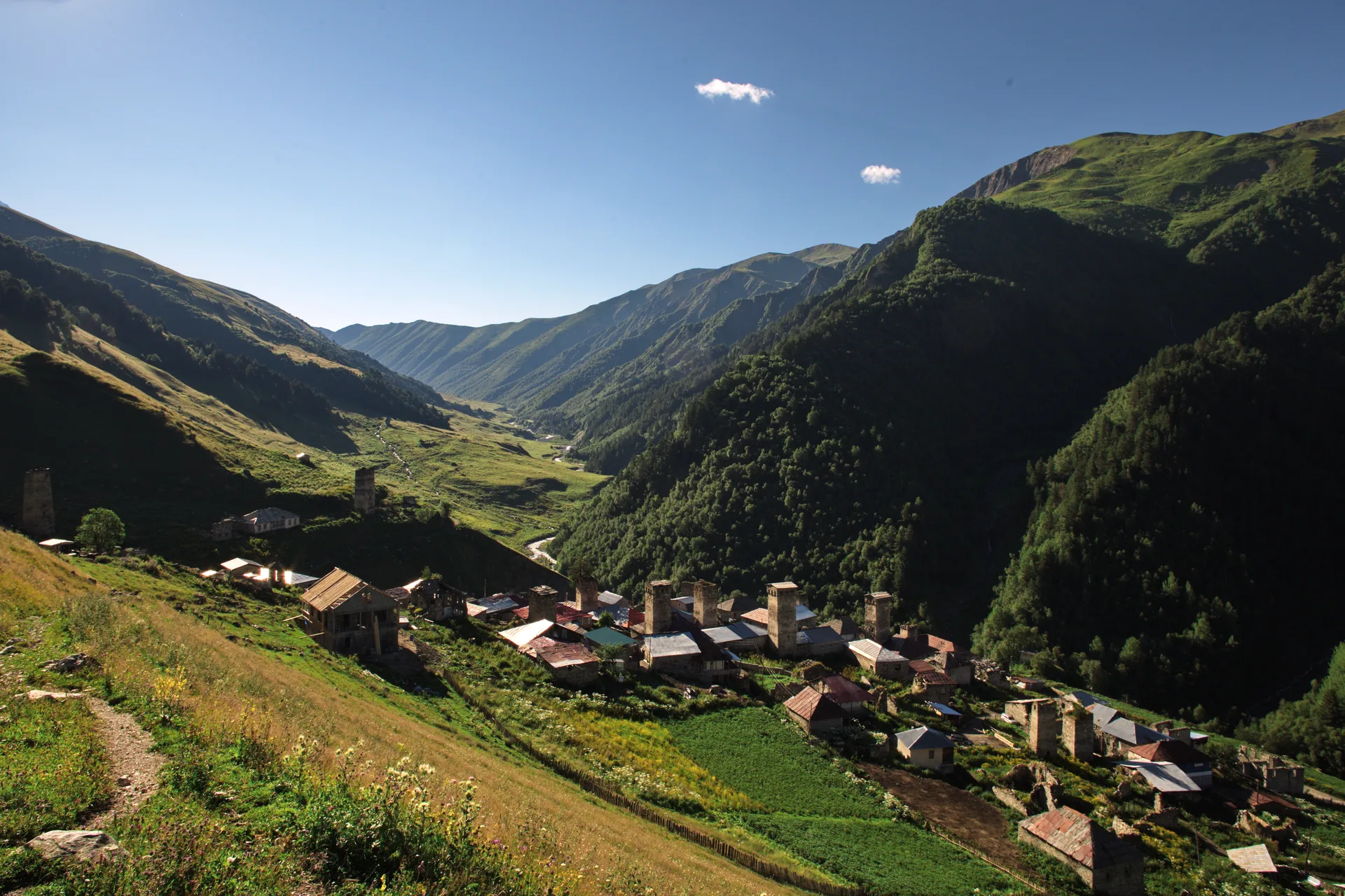 Adishi village low in a green valley between steep mountain slopes