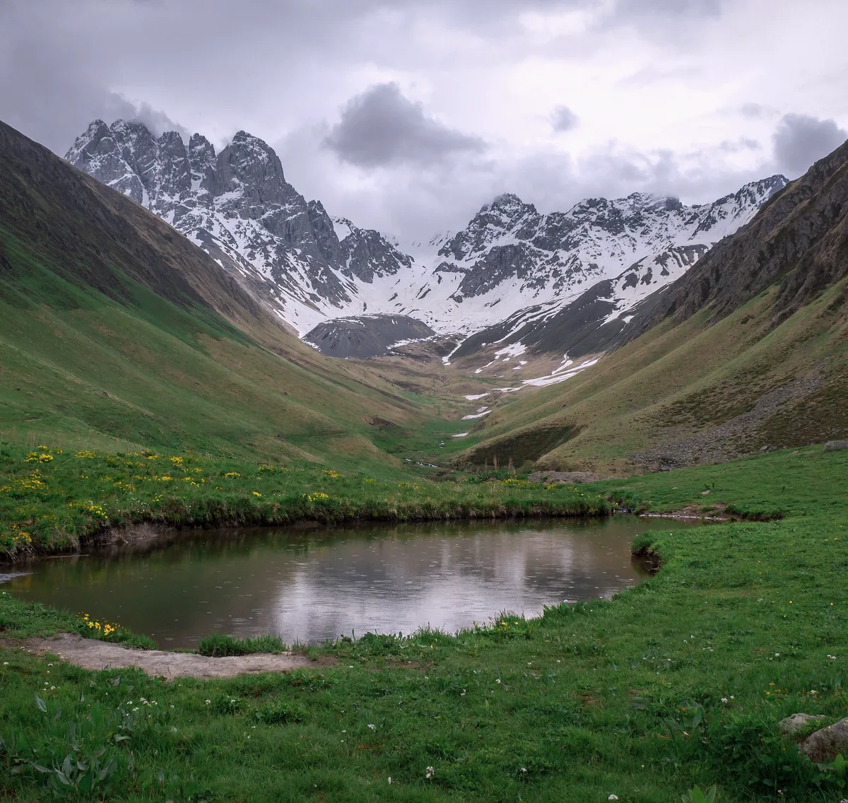 The jagged Chaukhi massif above a pond in the Juta valley, Kazbegi, in June