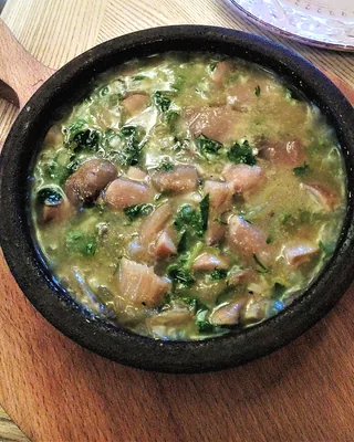 Chakapuli, lamb stewed with tarragon and green plums, in a black pan on a wooden board