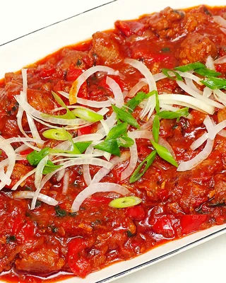 Beef and red pepper stew under slivers of onion and green onion