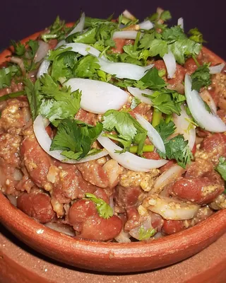 Lobio, red beans with walnut and coriander, in a clay pot topped with sliced onion