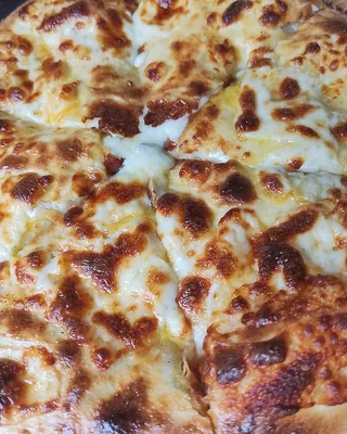 A round Megruli khachapuri with a second layer of cheese browned on top, cut into wedges