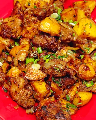 Fried pork and potatoes with onion and green onion