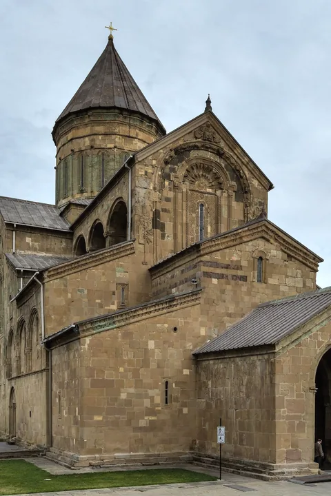 The stone cathedral of Svetitskhoveli with its tall conical dome under a grey autumn sky