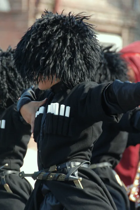 Dancers in black chokha and papakha hats at Tbilisoba