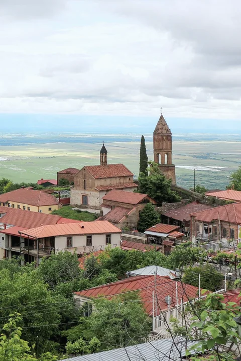 Red-roofed houses and a bell tower of Sighnaghi above a wide green valley