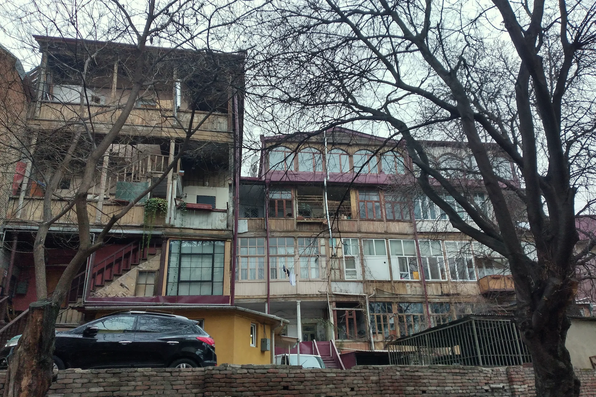 Carved wooden galleries on old houses in Daniel Chonkadze Street, bare winter trees in front
